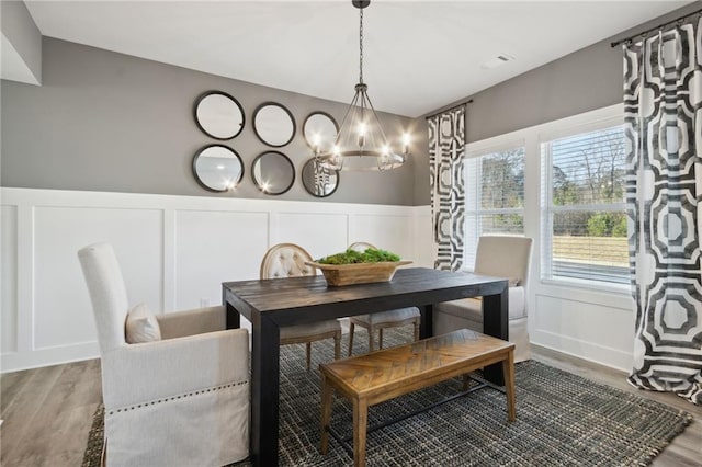 dining area featuring a decorative wall, wood finished floors, and a chandelier