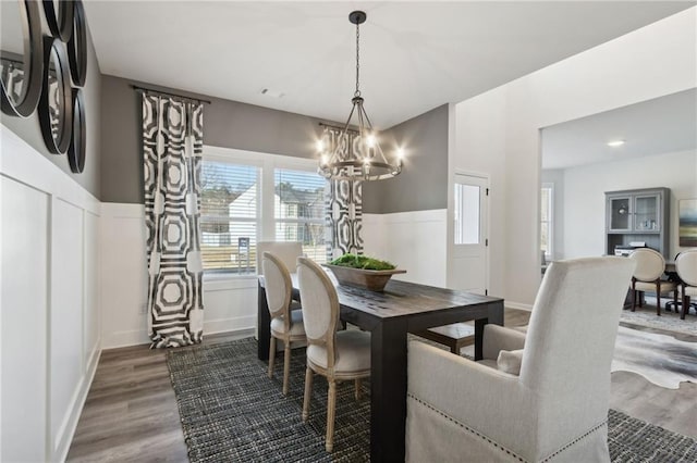 dining room featuring a chandelier, wainscoting, wood finished floors, and a decorative wall