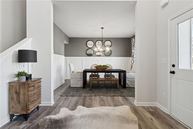 entryway with a decorative wall, wood finished floors, and a chandelier