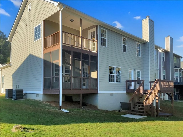 rear view of house with central AC unit, a balcony, a sunroom, and a lawn