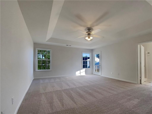 carpeted empty room with ceiling fan and a tray ceiling