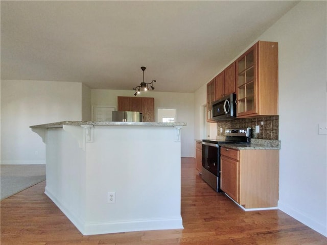 kitchen featuring light stone counters, appliances with stainless steel finishes, decorative backsplash, and light hardwood / wood-style flooring