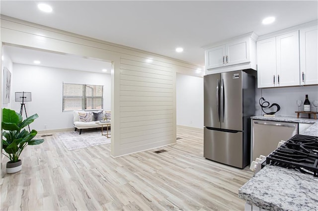 kitchen featuring light stone counters, recessed lighting, stainless steel appliances, white cabinets, and light wood finished floors