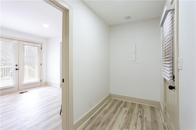 corridor with visible vents, light wood-style floors, baseboards, and french doors