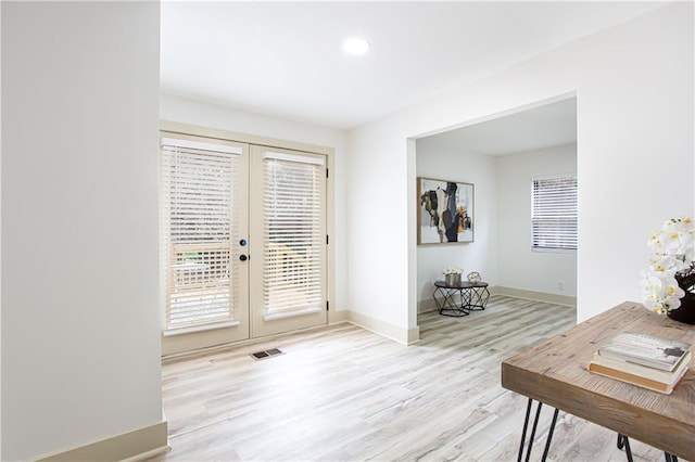 interior space with visible vents, wood finished floors, baseboards, and french doors