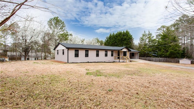 ranch-style home featuring brick siding, a front lawn, and fence