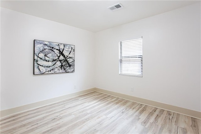 empty room with visible vents, light wood-style flooring, and baseboards