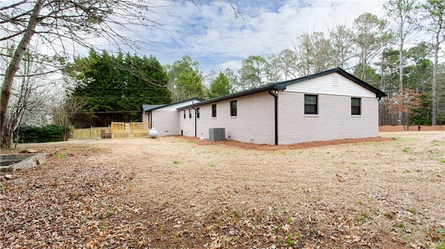 view of side of home with brick siding and central AC unit