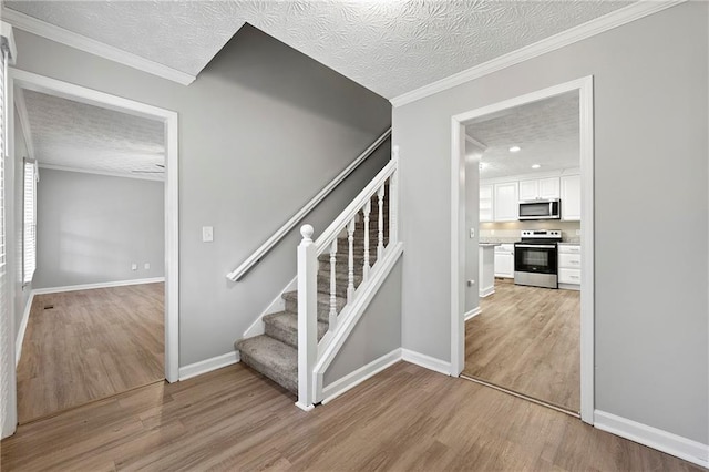 staircase with crown molding, wood-type flooring, and a textured ceiling