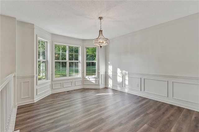733 Wesley Chapel Rd, Villa Rica, GA 30180 - unfurnished dining area featuring a decorative wall, a chandelier, a textured ceiling, dark wood-type flooring, and wainscoting