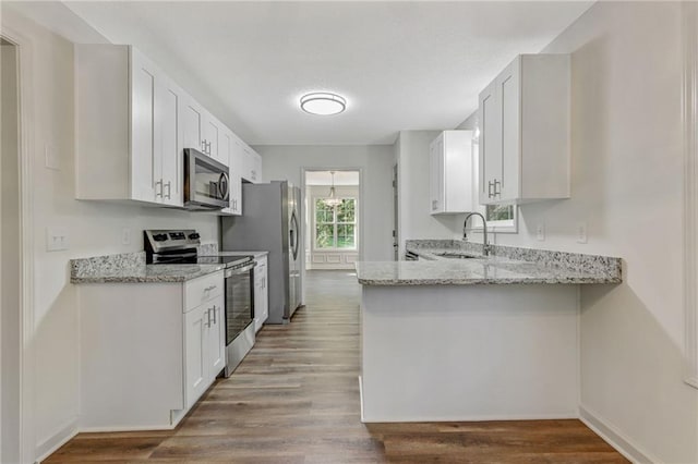 733 Wesley Chapel Rd, Villa Rica, GA 30180 - kitchen featuring stainless steel appliances, light stone counters, a peninsula, white cabinetry, and wood finished floors