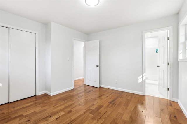 8298 Holly Dr, Jonesboro, GA 30238 - unfurnished bedroom featuring a closet, light wood-type flooring, baseboards, and connected bathroom