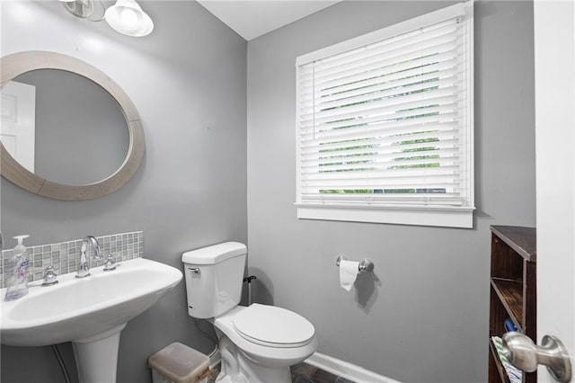 bathroom featuring a sink, decorative backsplash, and toilet