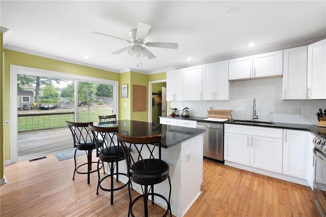 kitchen featuring visible vents, a breakfast bar, white cabinets, a sink, and stainless steel appliances