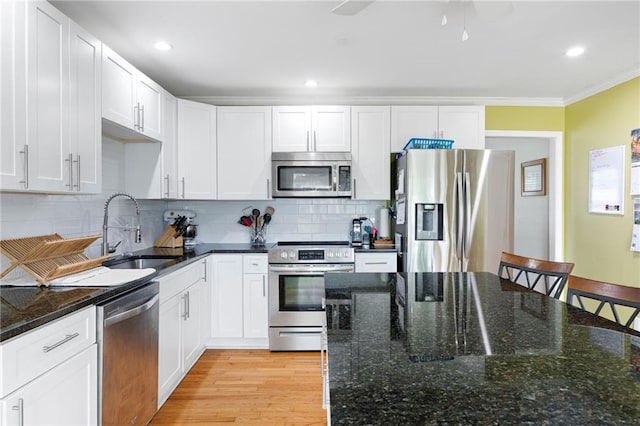 kitchen featuring white cabinets, appliances with stainless steel finishes, ornamental molding, and a sink