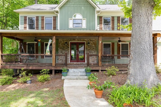 colonial house with board and batten siding, a ceiling fan, covered porch, and stone siding