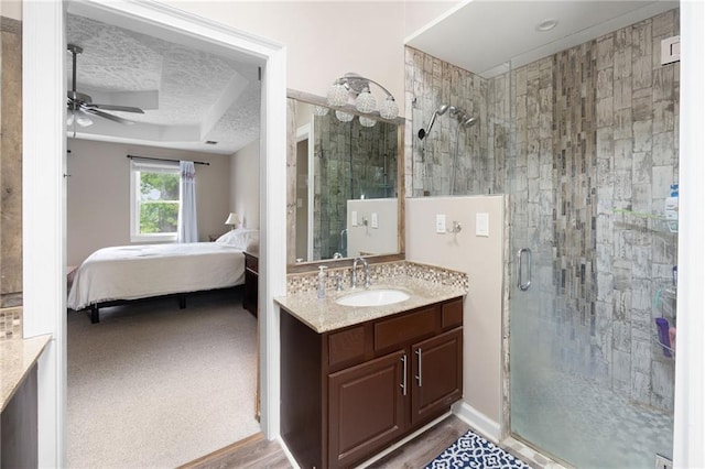 full bathroom with connected bathroom, ceiling fan, a textured ceiling, a shower stall, and a tray ceiling
