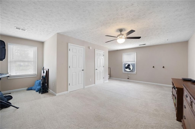 interior space with a ceiling fan, baseboards, visible vents, and light carpet