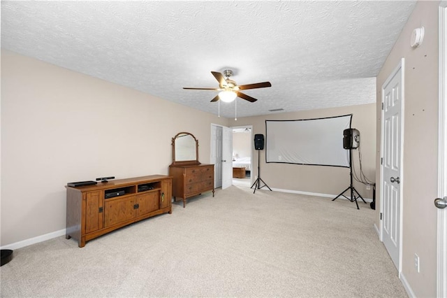 interior space with light colored carpet, a textured ceiling, ceiling fan, and baseboards
