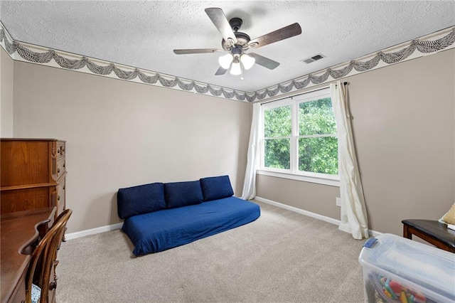 living area featuring a ceiling fan, carpet flooring, a textured ceiling, and visible vents