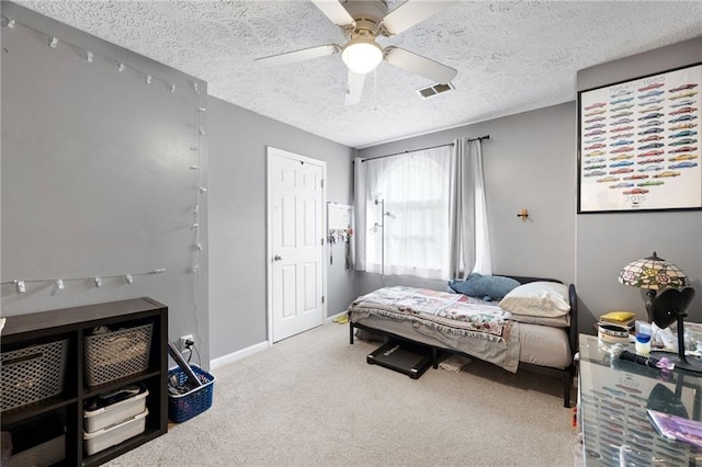 carpeted bedroom with baseboards, a textured ceiling, visible vents, and ceiling fan