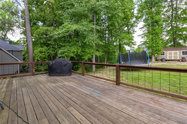 deck featuring a lawn, an outbuilding, a trampoline, and a storage unit