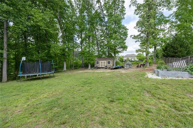 view of yard with an outdoor structure, fence, a vegetable garden, a storage unit, and a trampoline