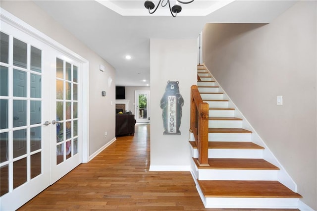 stairway featuring french doors, wood finished floors, baseboards, a chandelier, and recessed lighting