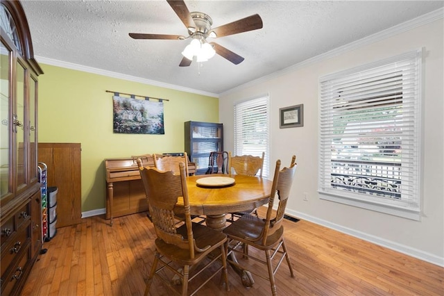 dining room featuring a textured ceiling, ornamental molding, and light wood-style floors