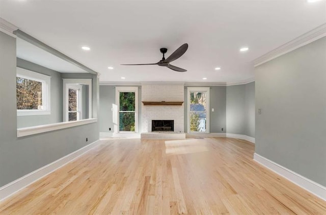 unfurnished living room featuring light hardwood / wood-style flooring, crown molding, and a brick fireplace