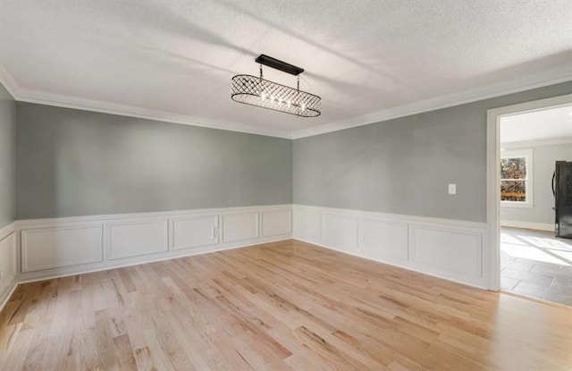 empty room featuring light hardwood / wood-style flooring, a textured ceiling, and crown molding