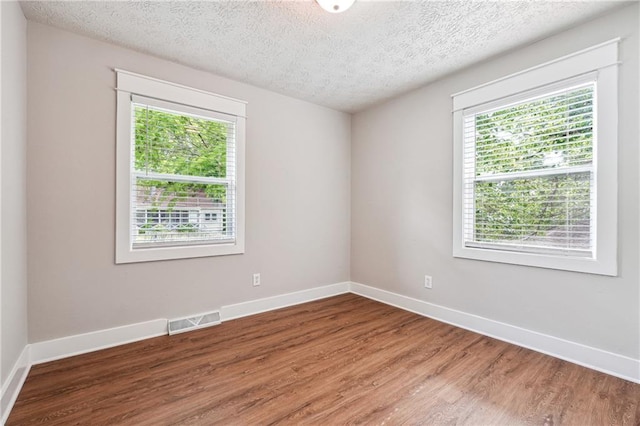 unfurnished room with wood finished floors, baseboards, and a textured ceiling