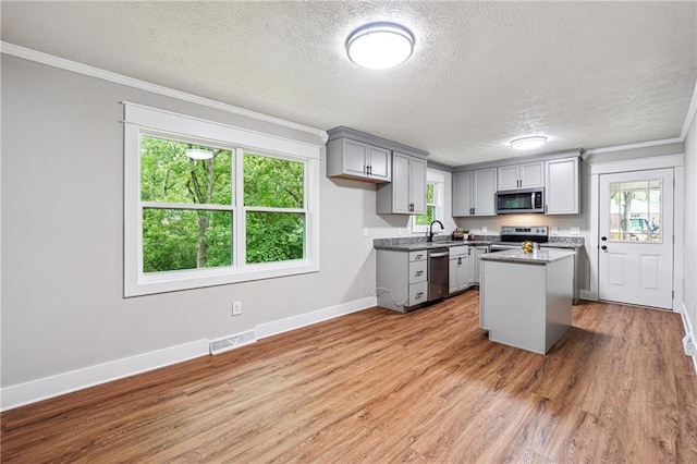 kitchen featuring stainless steel appliances, gray cabinetry, a textured ceiling, a kitchen island, and baseboards