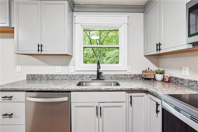 kitchen featuring stainless steel appliances, a sink, and light stone countertops