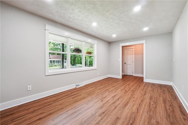 spare room featuring recessed lighting, wood finished floors, a textured ceiling, and baseboards