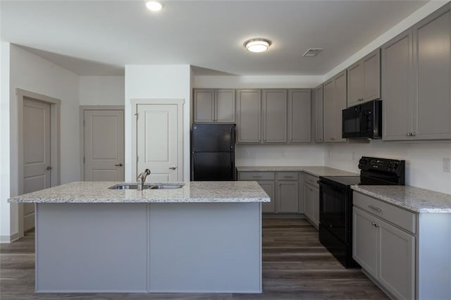 kitchen with sink, an island with sink, dark wood-type flooring, and black appliances