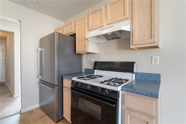 kitchen featuring range with gas stovetop, light brown cabinetry, freestanding refrigerator, a textured ceiling, and under cabinet range hood