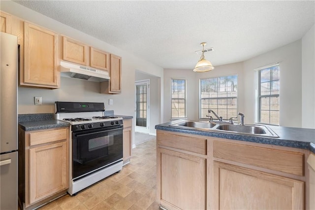 kitchen with visible vents, range with gas stovetop, under cabinet range hood, light brown cabinets, and a sink