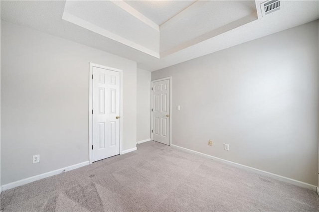 spare room featuring baseboards, visible vents, a tray ceiling, a textured ceiling, and carpet flooring