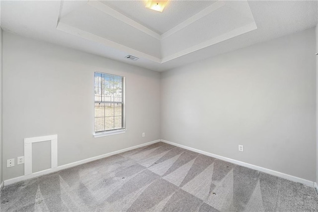 carpeted spare room featuring a raised ceiling, visible vents, a textured ceiling, and baseboards