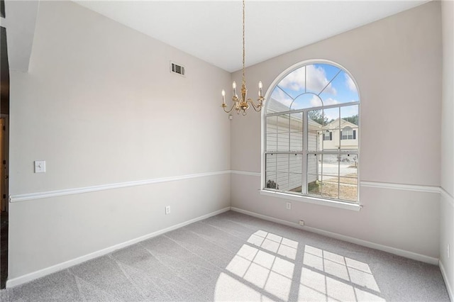 carpeted spare room with baseboards, visible vents, and an inviting chandelier