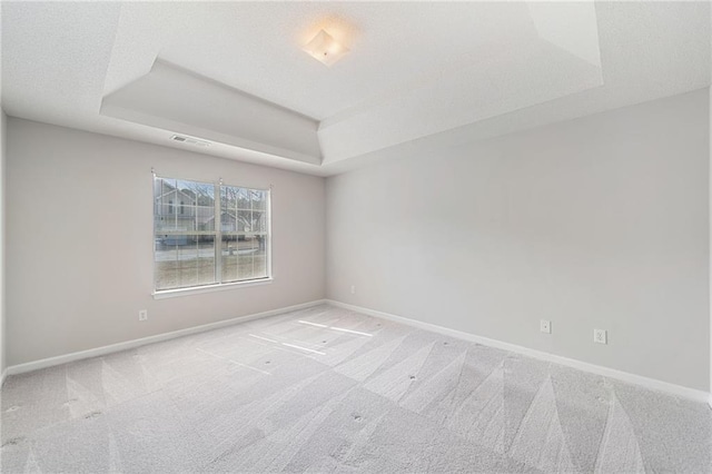 carpeted empty room with a raised ceiling, visible vents, a textured ceiling, and baseboards