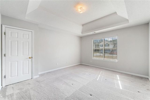 carpeted empty room with a tray ceiling, visible vents, a textured ceiling, and baseboards