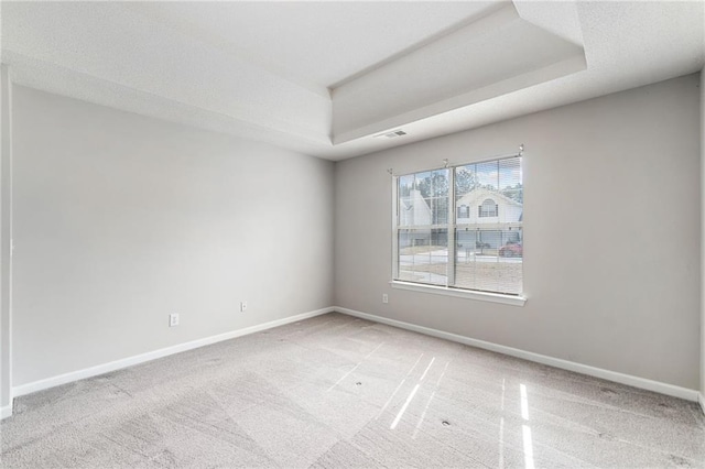 spare room featuring carpet floors, baseboards, visible vents, and a tray ceiling