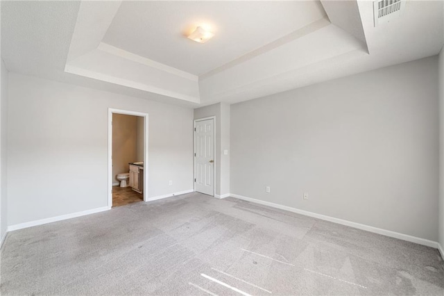 carpeted empty room with a raised ceiling, visible vents, and baseboards