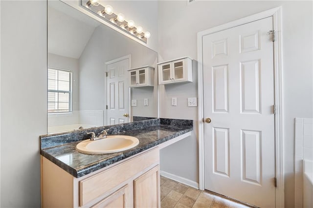 bathroom with a washtub, vaulted ceiling, and vanity