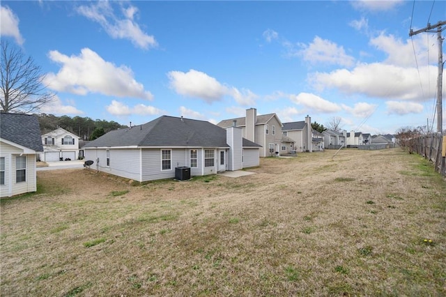 rear view of house featuring a residential view, central air condition unit, fence, and a lawn