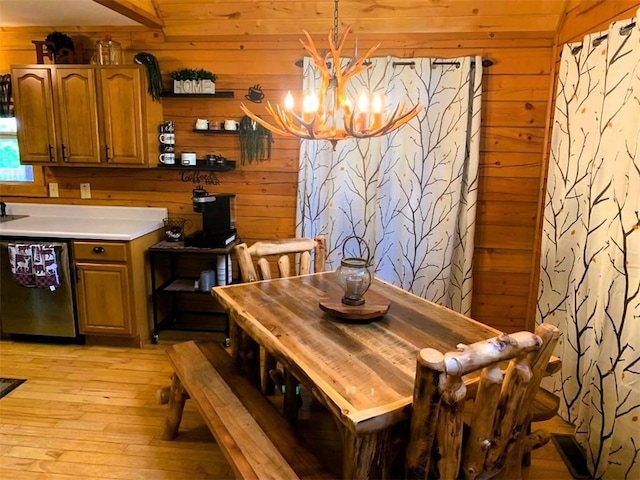 dining room with a notable chandelier, light wood-type flooring, and wood walls