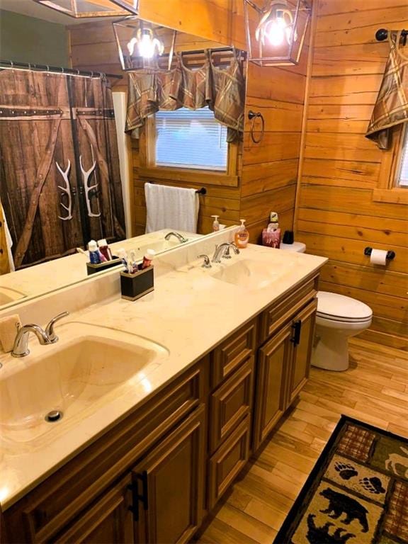 bathroom with vanity, wood-type flooring, a shower with curtain, toilet, and wood walls