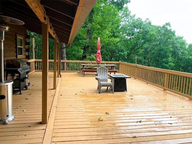 wooden terrace featuring area for grilling and an outdoor fire pit